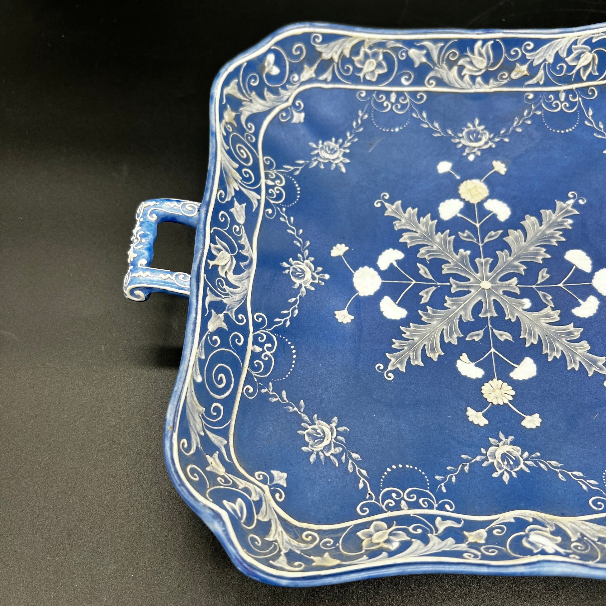 Decorative blue tray with white floral patterns on a black background