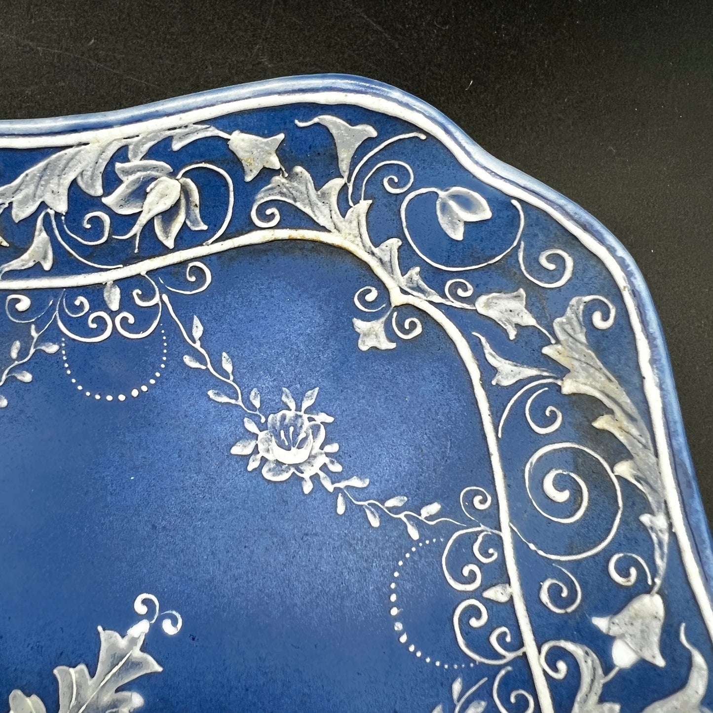 Decorative blue plate with intricate white floral patterns on a black background