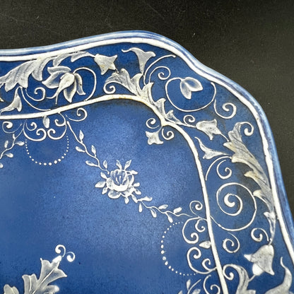 Decorative blue plate with intricate white floral patterns on a black background