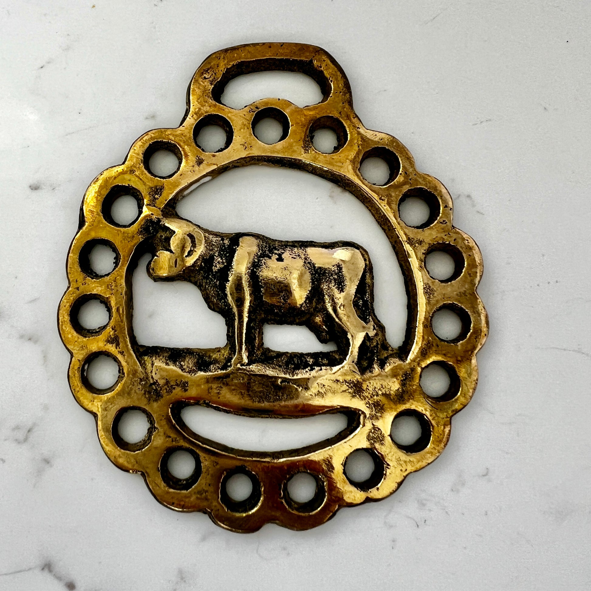 Vintage cow horse brass medallion attached to brown leather keychain with brass hardware.