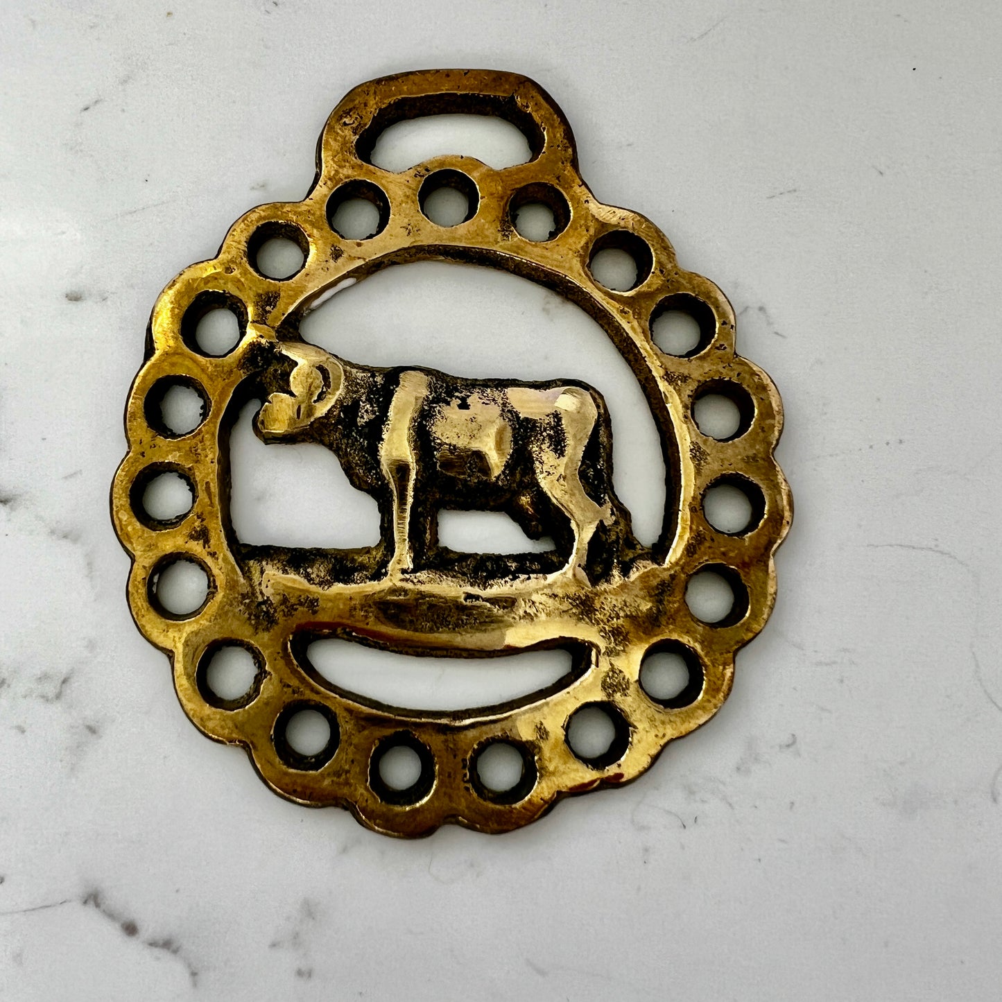 Vintage cow horse brass medallion attached to brown leather keychain with brass hardware.