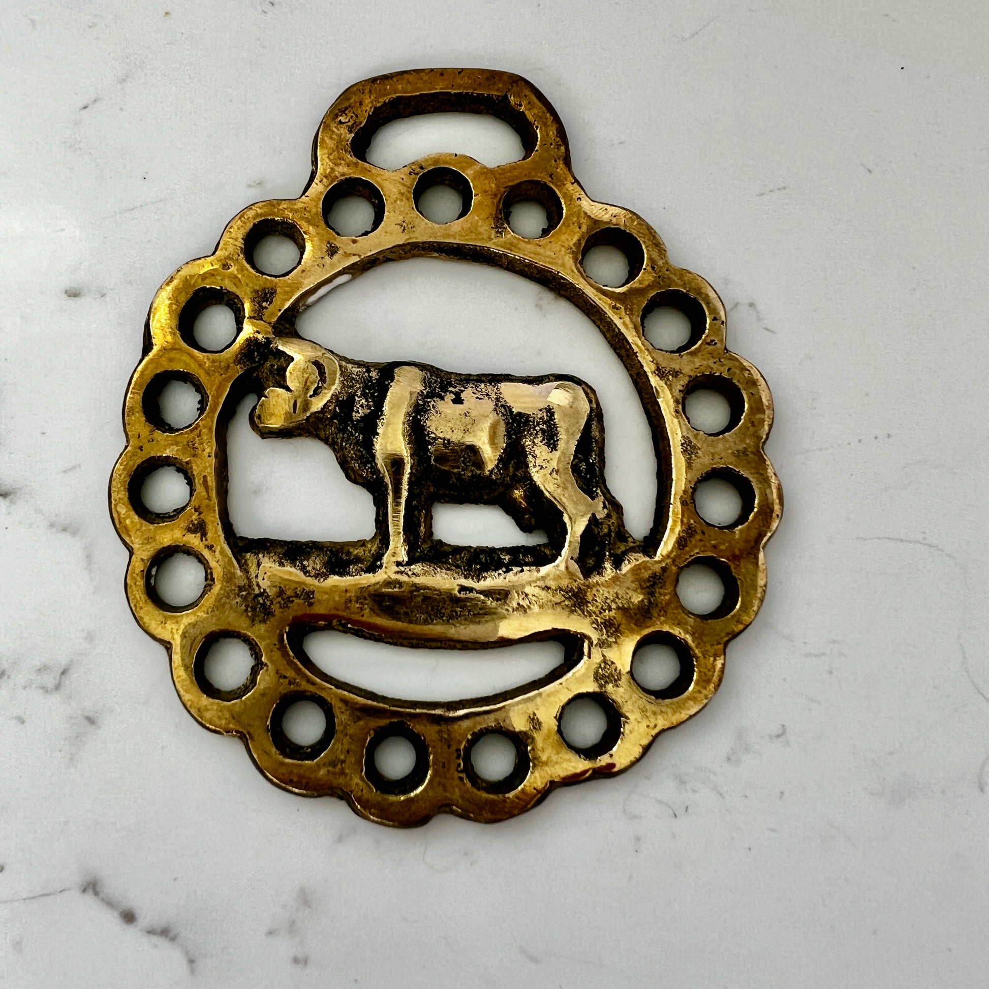 Vintage cow horse brass medallion attached to brown leather keychain with brass hardware.