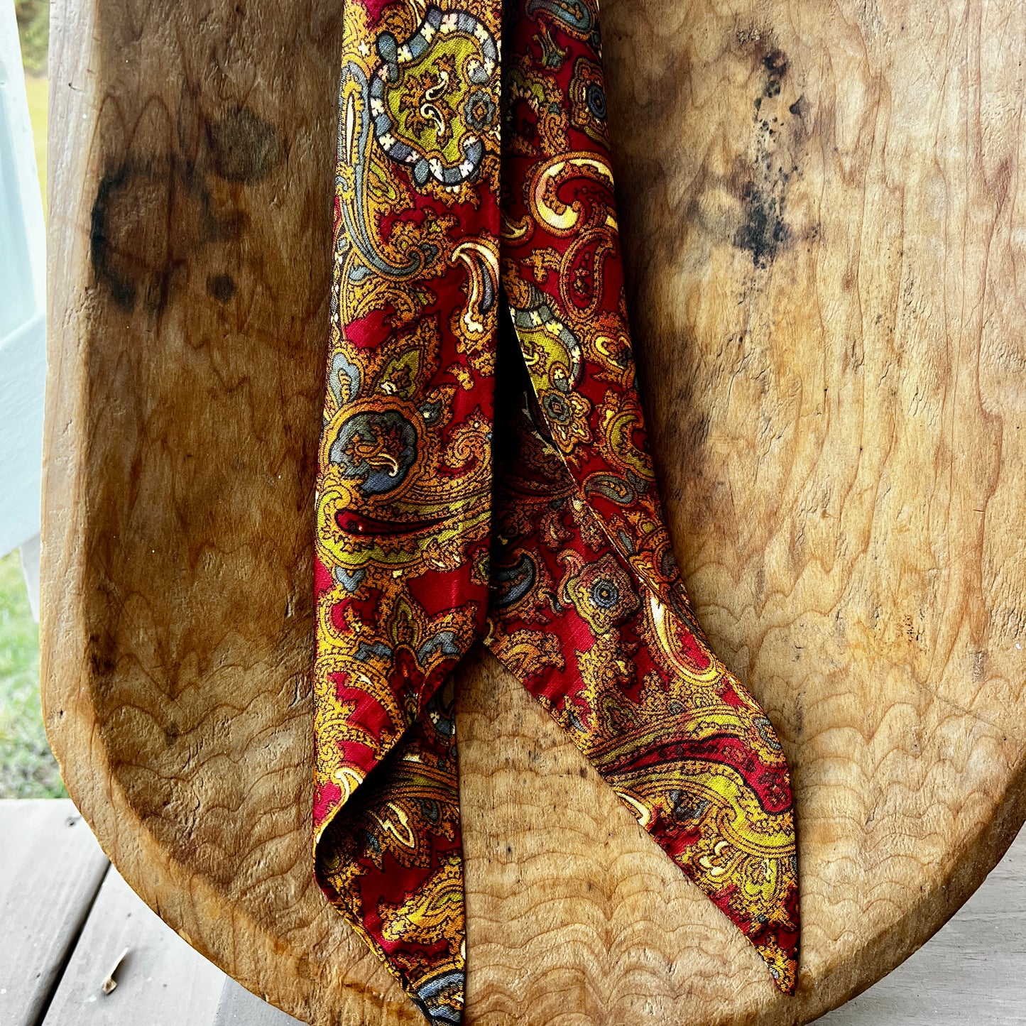 Decorative red and gold paisley scarf on a wooden surface