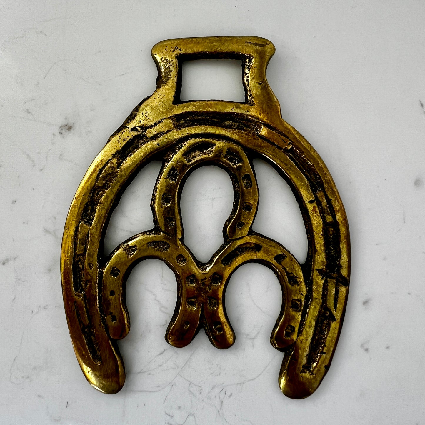 Vintage double horseshoe brass medallion necklace with dark multi-strand beads and leather connector.