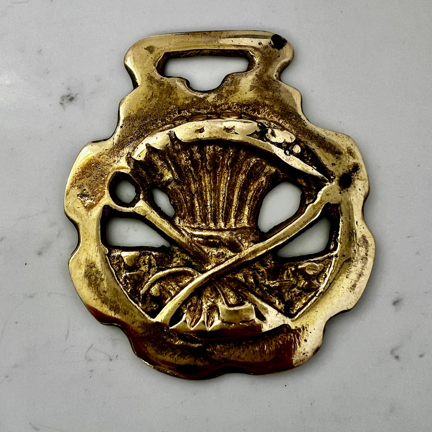 Vintage scythe and wheat horse brass medallion attached to triple-strand black and cream beaded necklace with leather connector.