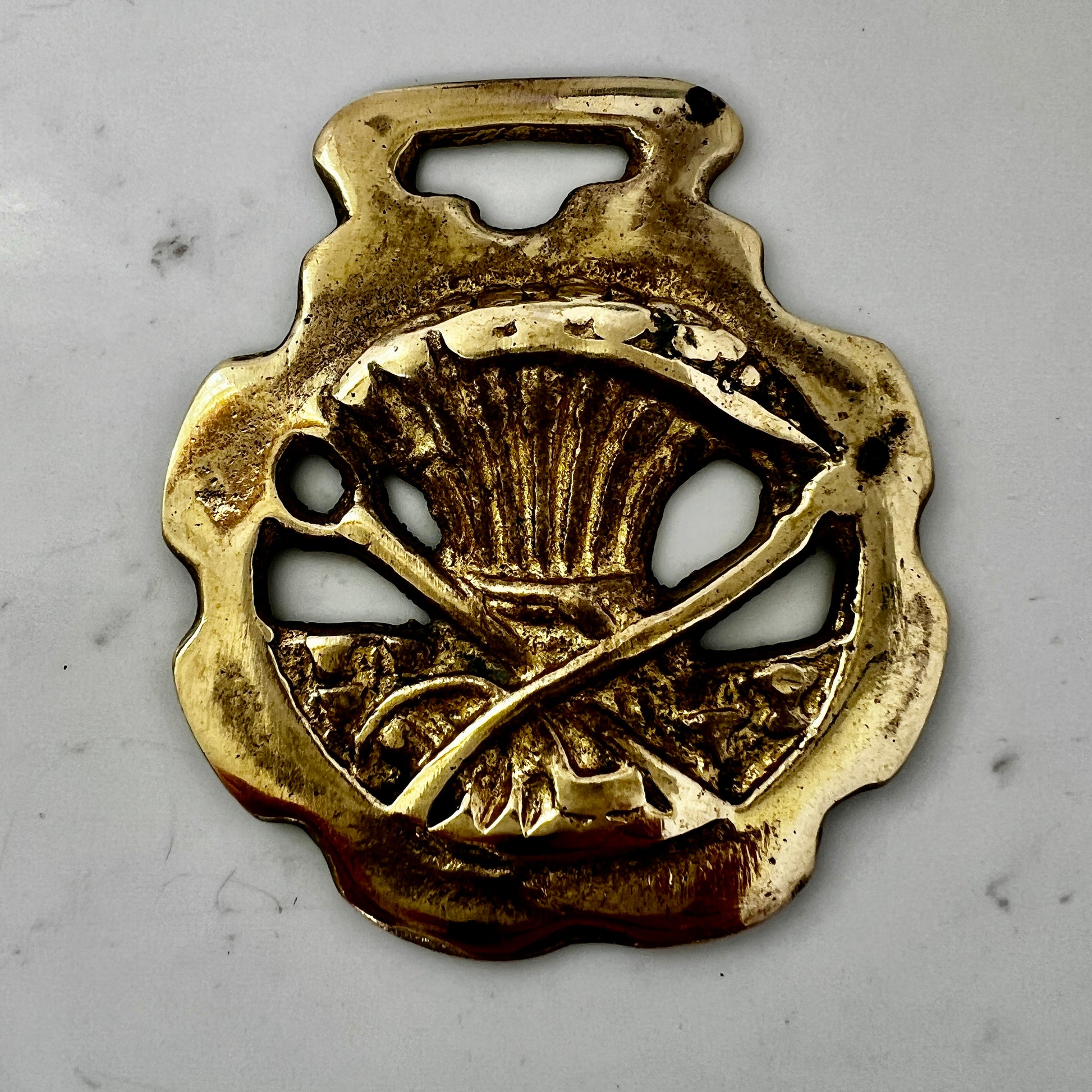 Vintage scythe and wheat horse brass medallion attached to triple-strand black and cream beaded necklace with leather connector.