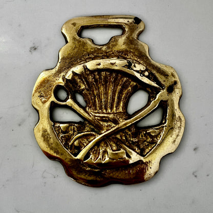 Vintage scythe and wheat horse brass medallion attached to triple-strand black and cream beaded necklace with leather connector.