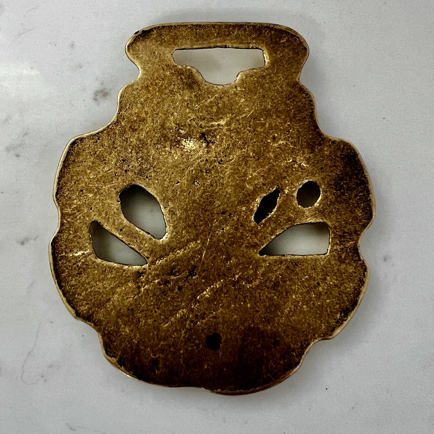 Vintage scythe and wheat horse brass medallion attached to triple-strand black and cream beaded necklace with leather connector.