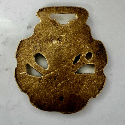 Vintage scythe and wheat horse brass medallion attached to triple-strand black and cream beaded necklace with leather connector.