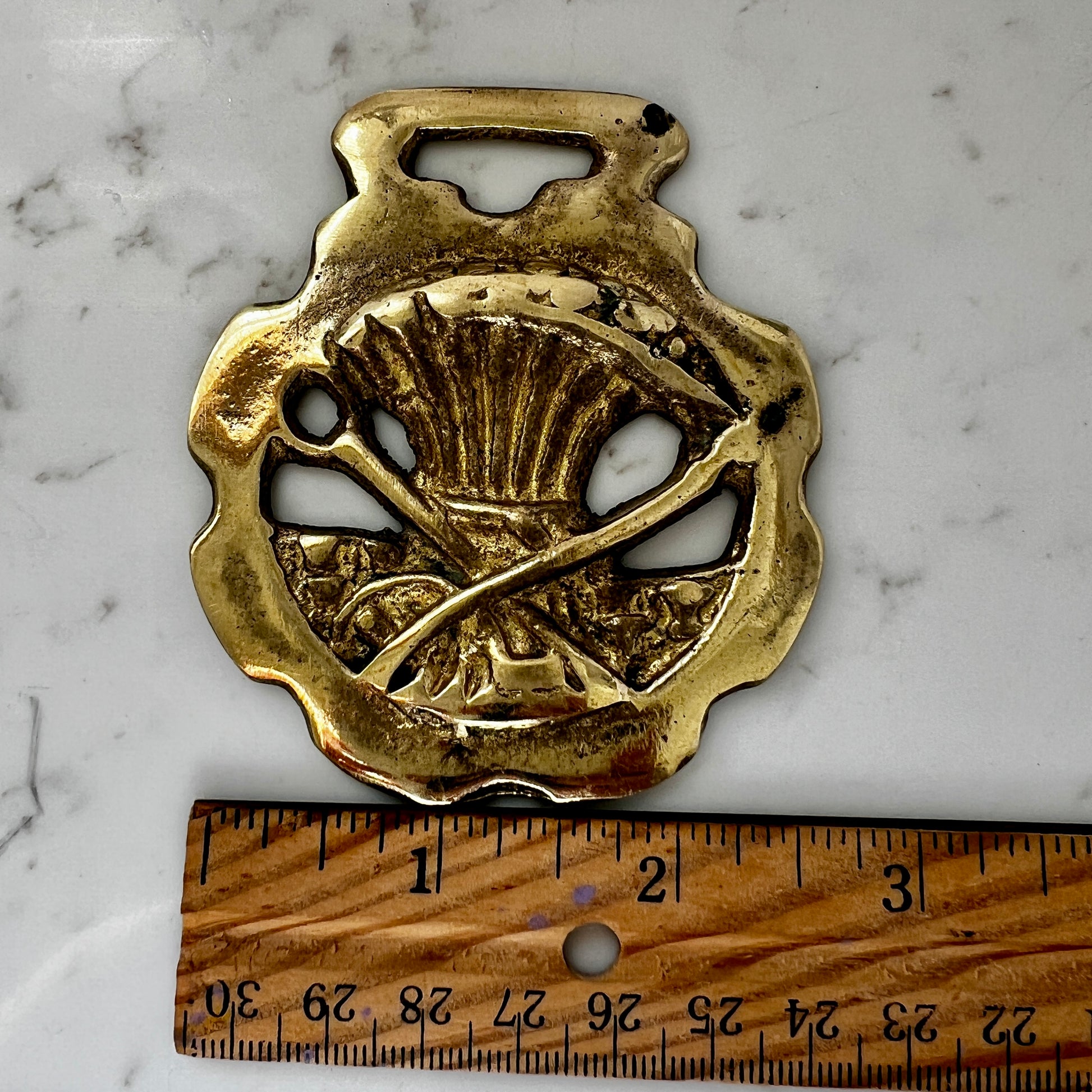 Vintage scythe and wheat horse brass medallion attached to triple-strand black and cream beaded necklace with leather connector.