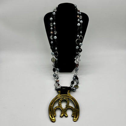 Vintage double horseshoe brass medallion necklace with dark multi-strand beads and leather connector.