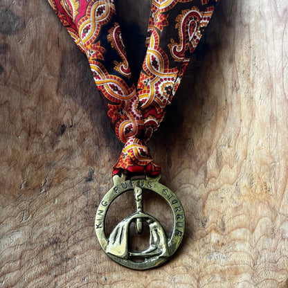 Vintage King Rufus Stirrup brass medallion necklace with red paisley scarf, equestrian jewelry.