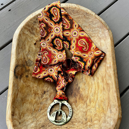 Vintage King Rufus Stirrup brass medallion necklace with red paisley scarf, equestrian jewelry.