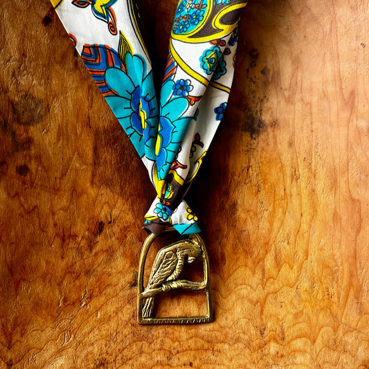 Vintage parrot brass medallion necklace with vibrant retro floral scarf, boho statement jewelry.