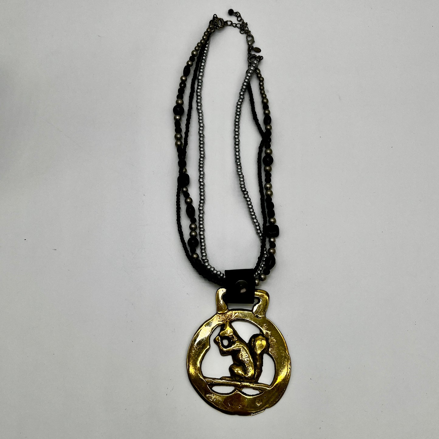 Vintage squirrel brass horse medallion on multi-strand black and silver beaded necklace with leather connector.
