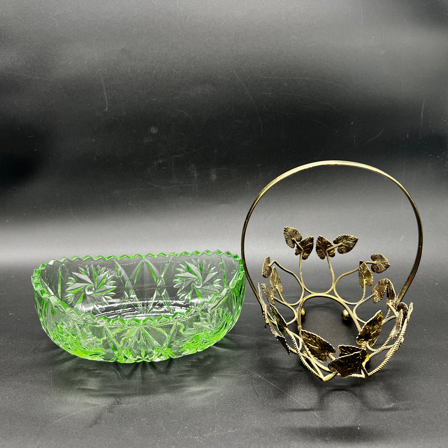 Green glass bowl and decorative metal basket on a dark background
