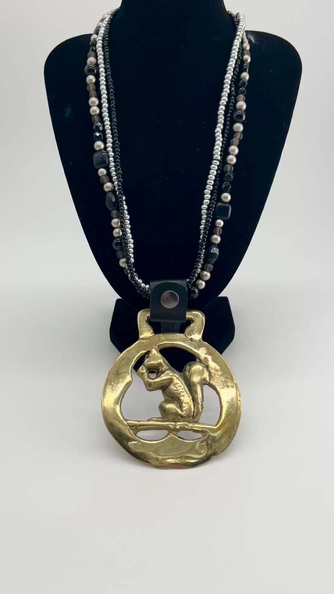 Vintage squirrel brass horse medallion on multi-strand black and silver beaded necklace with leather connector.VIDEO